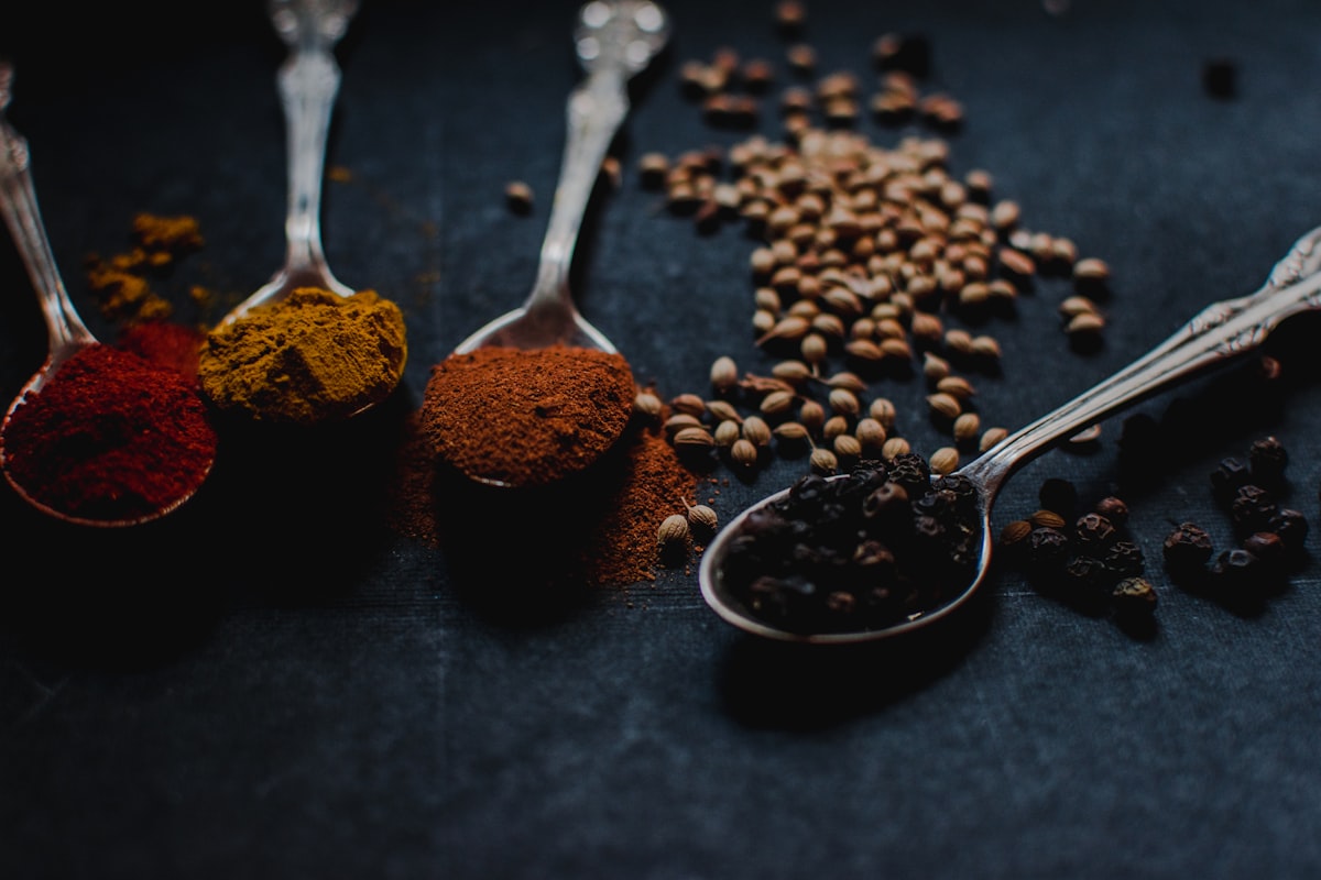 Black peppercorns and ground spices in spoons